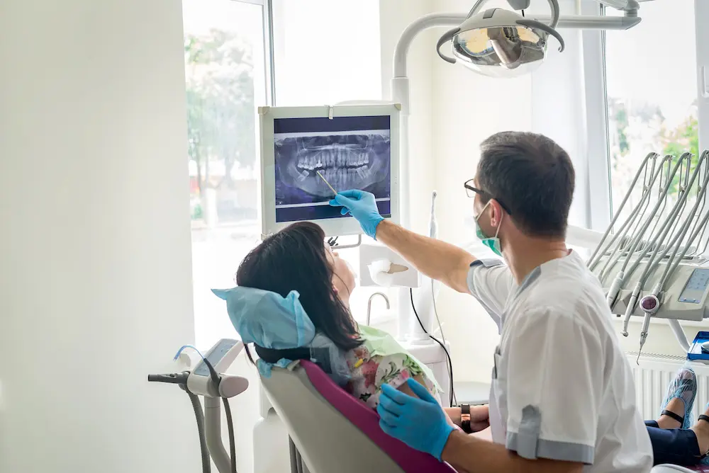 Dentist reviewing new x-rays with a patient after medical malpractice happened with the previous dentist