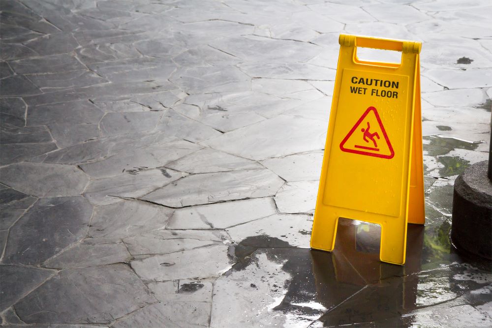 A wet floor caution sign outside of a business to prevent slip and fall accidents.