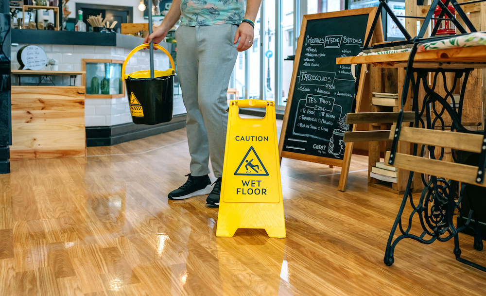 worker putting up a caution sign after being sued for a slip and fall case in florida